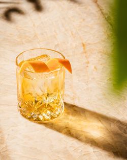 Cocktail with orange peel in a crystal glass on a marble table, representing Casa Madera West Hollywood's cocktail offerings.