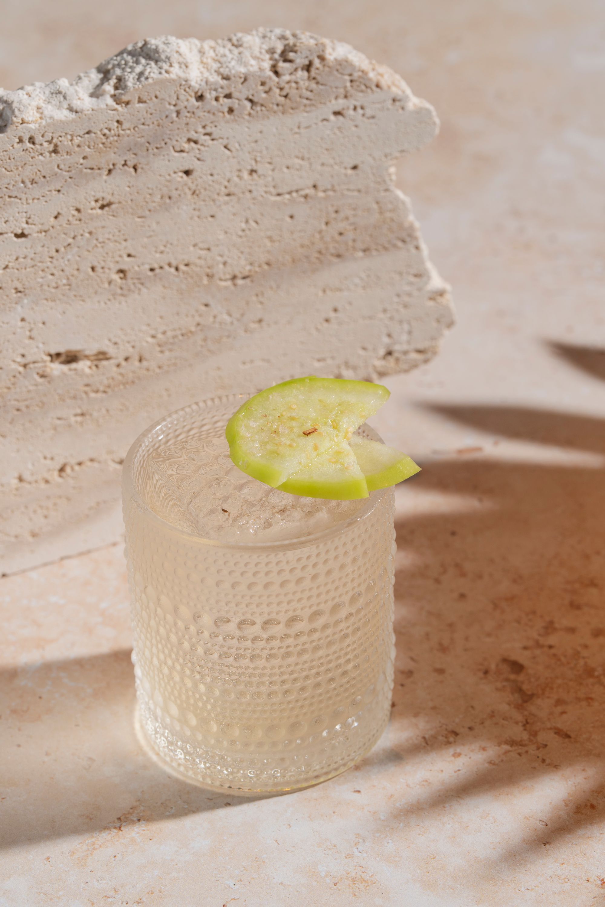 Cocktail served in a textured glass with a slice of green garnish on a stone surface at Casa Madera West Hollywood.
